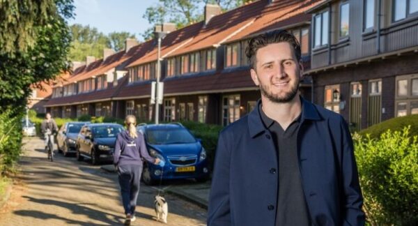 Man staand voor rijtjeswoningen.