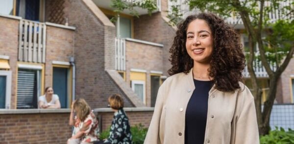 Vrouw staand voor een appartementencomplex.