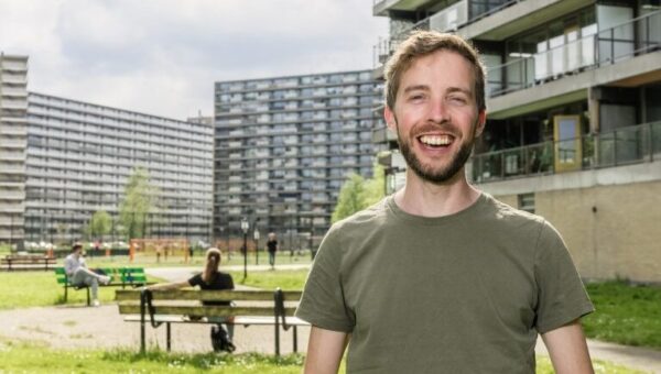 Man staand voor park met op de achtergrond flatwoningen.