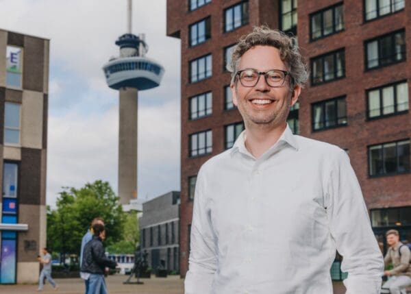 Man staand voor gebouw met Euromast op de achtergrond