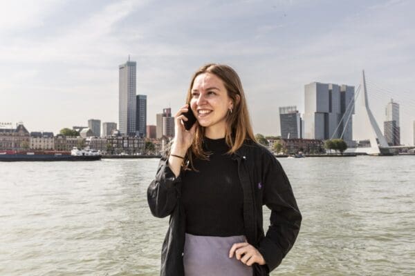 Vrouw staand aan de maas voor de Erasmusbrug.