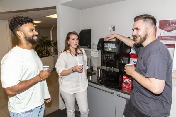 Drie collega's bij het koffiezetapparaat
