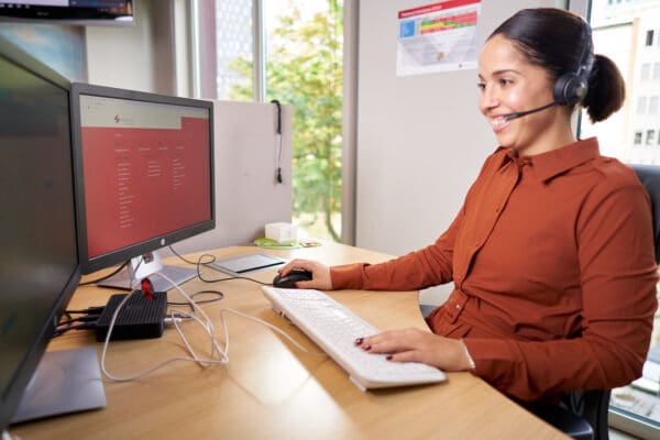 Vrouw zittend achter bureau met computerscherm